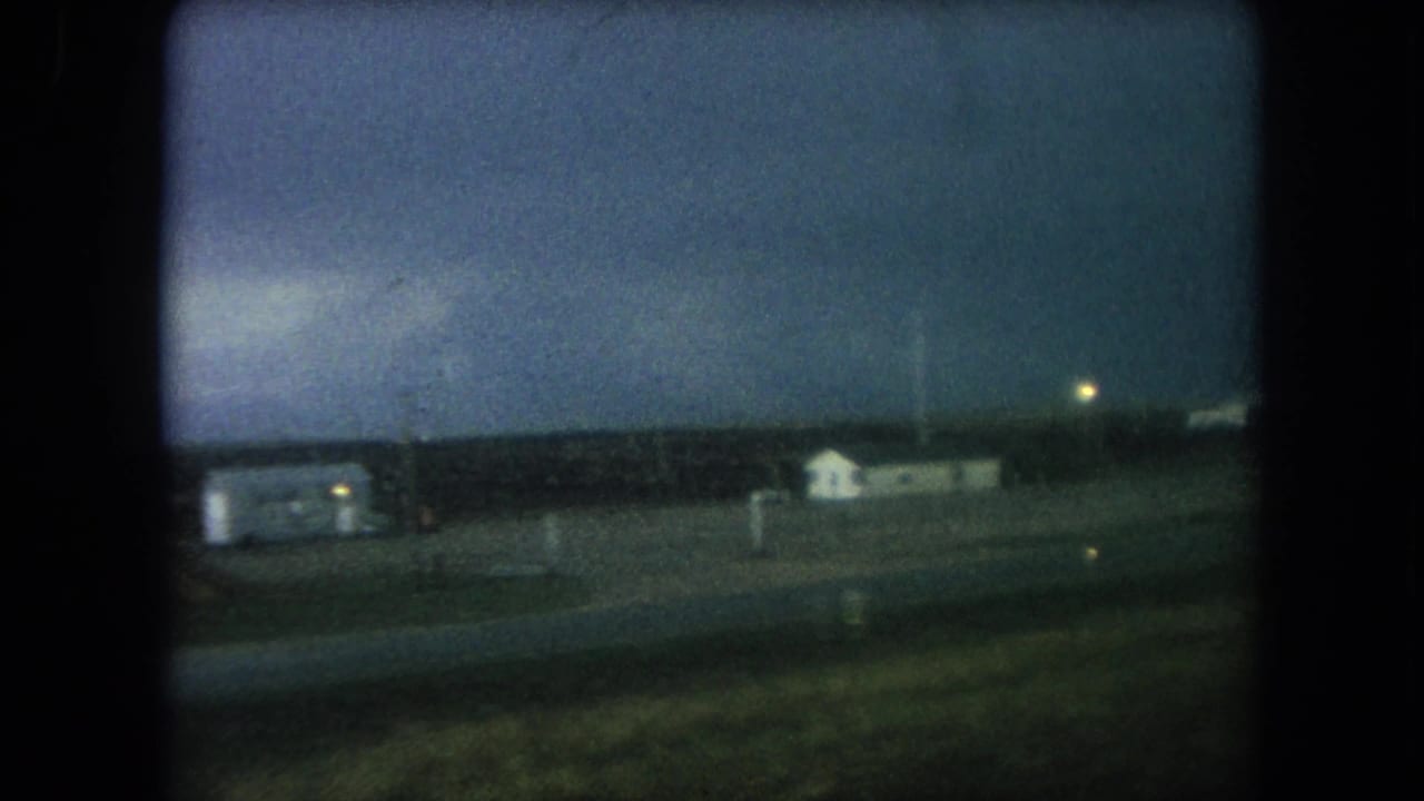 Roadside buildings and a darkening sky viewed from a moving vehicle.