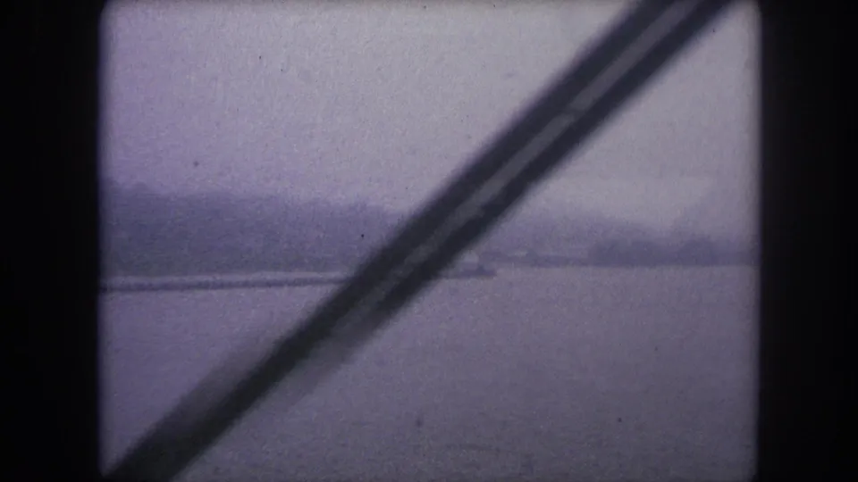 1962 8mm view over water in Colorado, partly blocked by a diagonal bridge or window support.