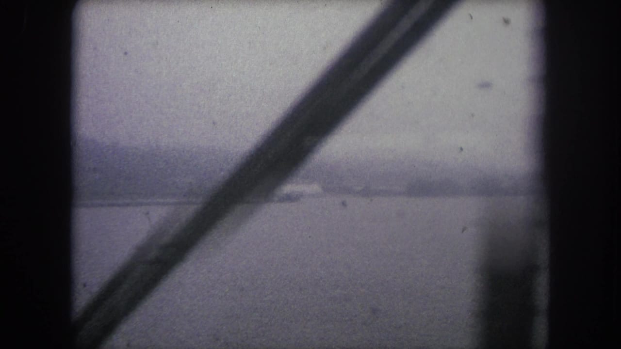 Bridge supports frame a broad gray river with a faint far shore under overcast light.