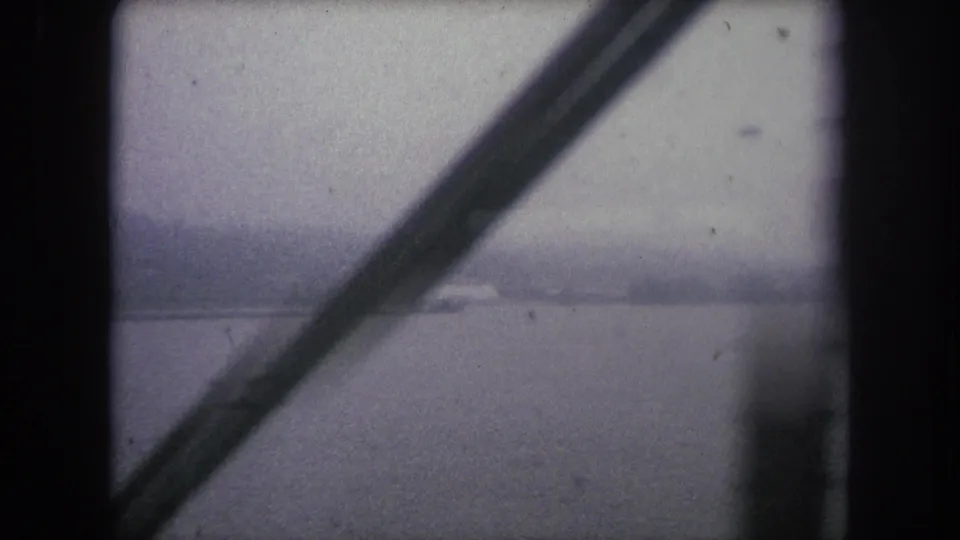 Winter Park, Colorado 1962 home-movie frame with dark bridge structure cutting across a foggy river landscape.