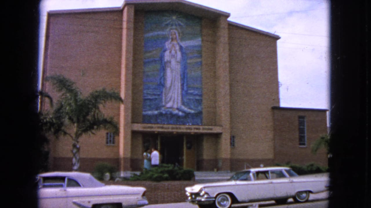 Barrington, Illinois church exterior in 1963 showing the mosaic-covered facade, parked white cars, palms, and two adults at the entrance.