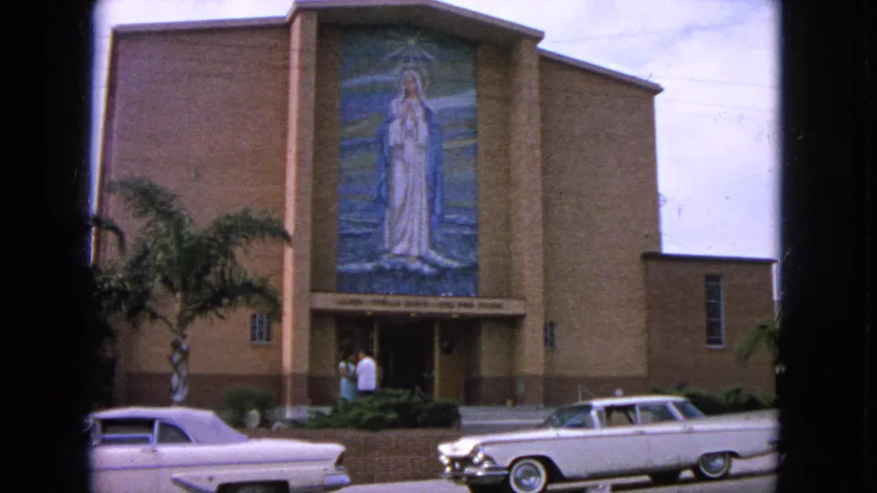 Barrington, Illinois church exterior in 1963 showing the mosaic-covered facade, parked white cars, palms, and two adults at the entrance.