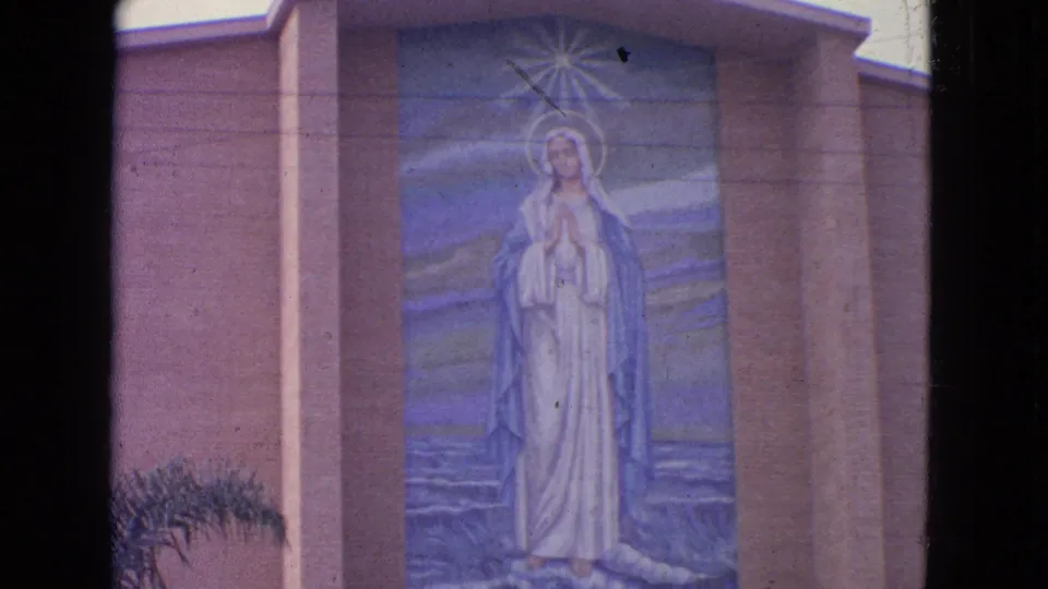 1963 Barrington, Illinois 8mm frame showing a Virgin Mary mural in white and blue on a church exterior wall.