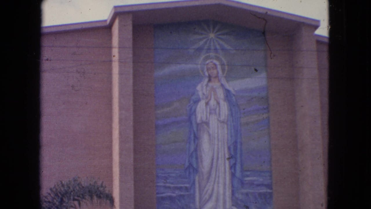 1963 Barrington, Illinois 8mm frame showing a Virgin Mary mural set into a church facade with a radiant halo motif.