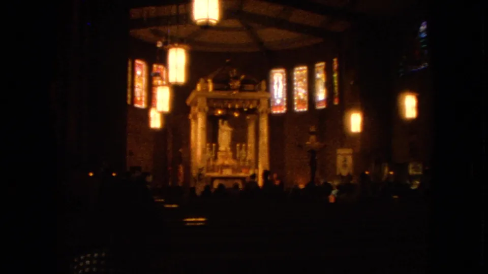 1963 Barrington, Illinois 8mm frame showing a dim church interior with warm lanterns, stained glass, and an altar statue.