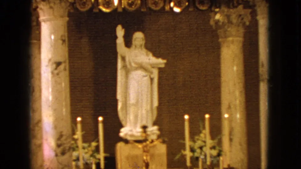 White saint statue and tall candles inside a Barrington church, filmed on 8mm in 1963.