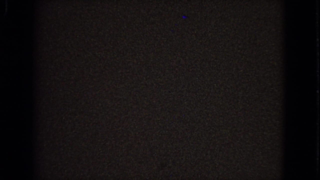 Dark 8mm frame from the 1963 Barrington clip, with only faint interior detail and film texture visible after the stained-glass view shifts away.