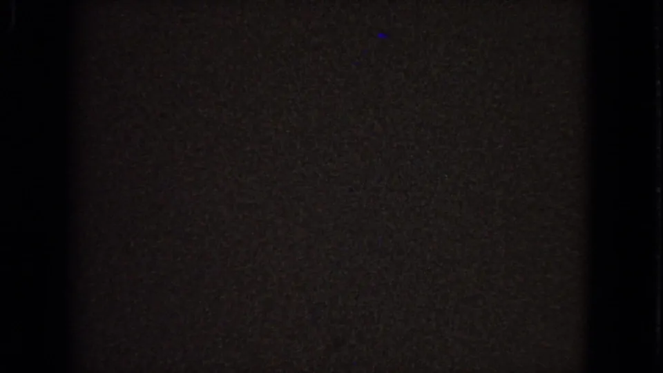 Dark 8mm frame from the 1963 Barrington clip, with only faint interior detail and film texture visible after the stained-glass view shifts away.