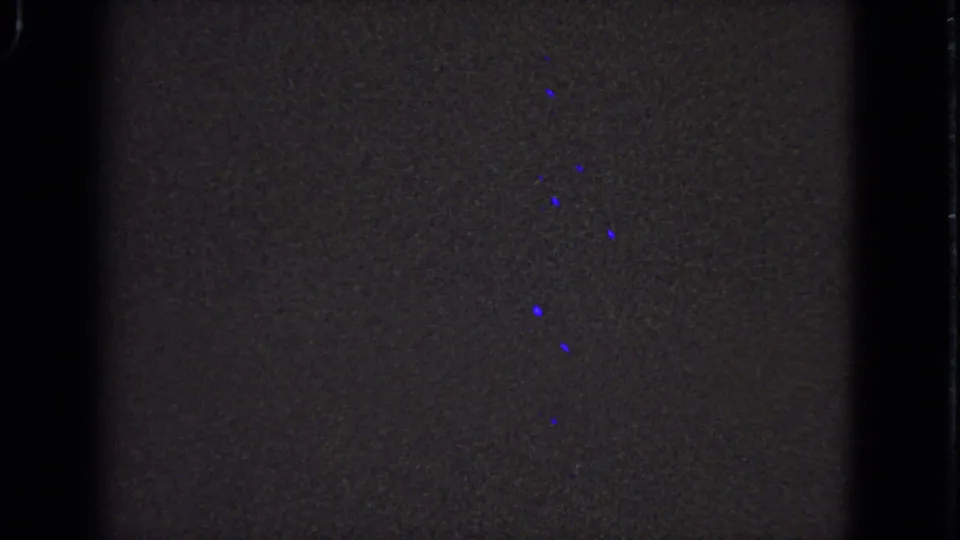 Underexposed 1963 8mm frame with mostly dark film area, blue specks, and visible contact-sheet borders.