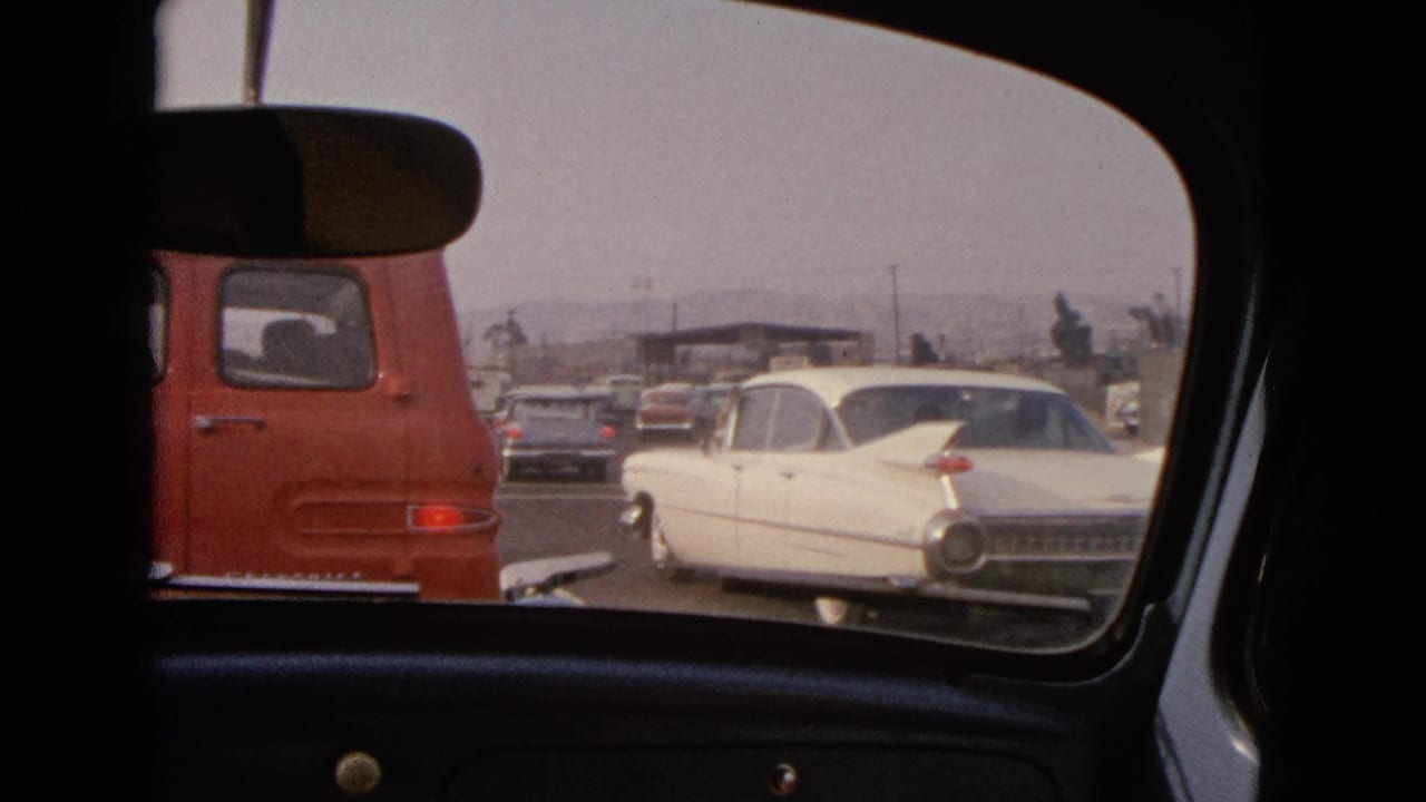 1963 Barrington, Illinois road scene framed by a car interior, showing a red van and white classic sedan in traffic.