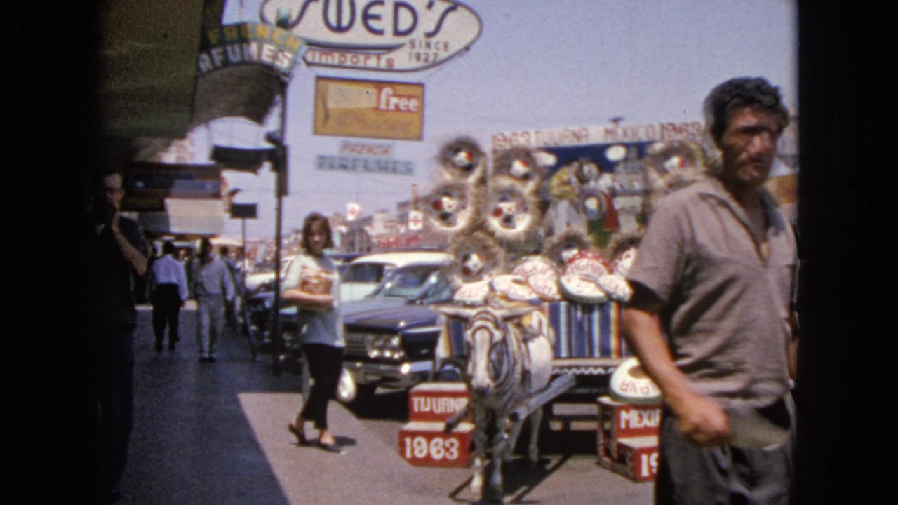 1963 Barrington, Illinois street scene with a man passing a donkey cart loaded with sombreros and decorations near shops and cars.