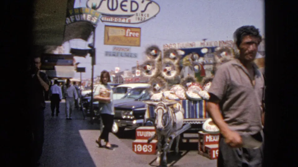1963 Barrington, Illinois street scene with a man passing a donkey cart loaded with sombreros and decorations near shops and cars.