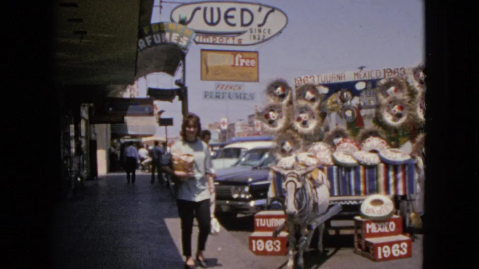 A 1963 Barrington, Illinois home-movie frame shows a woman approaching near a donkey cart decorated with sombreros and wreaths.
