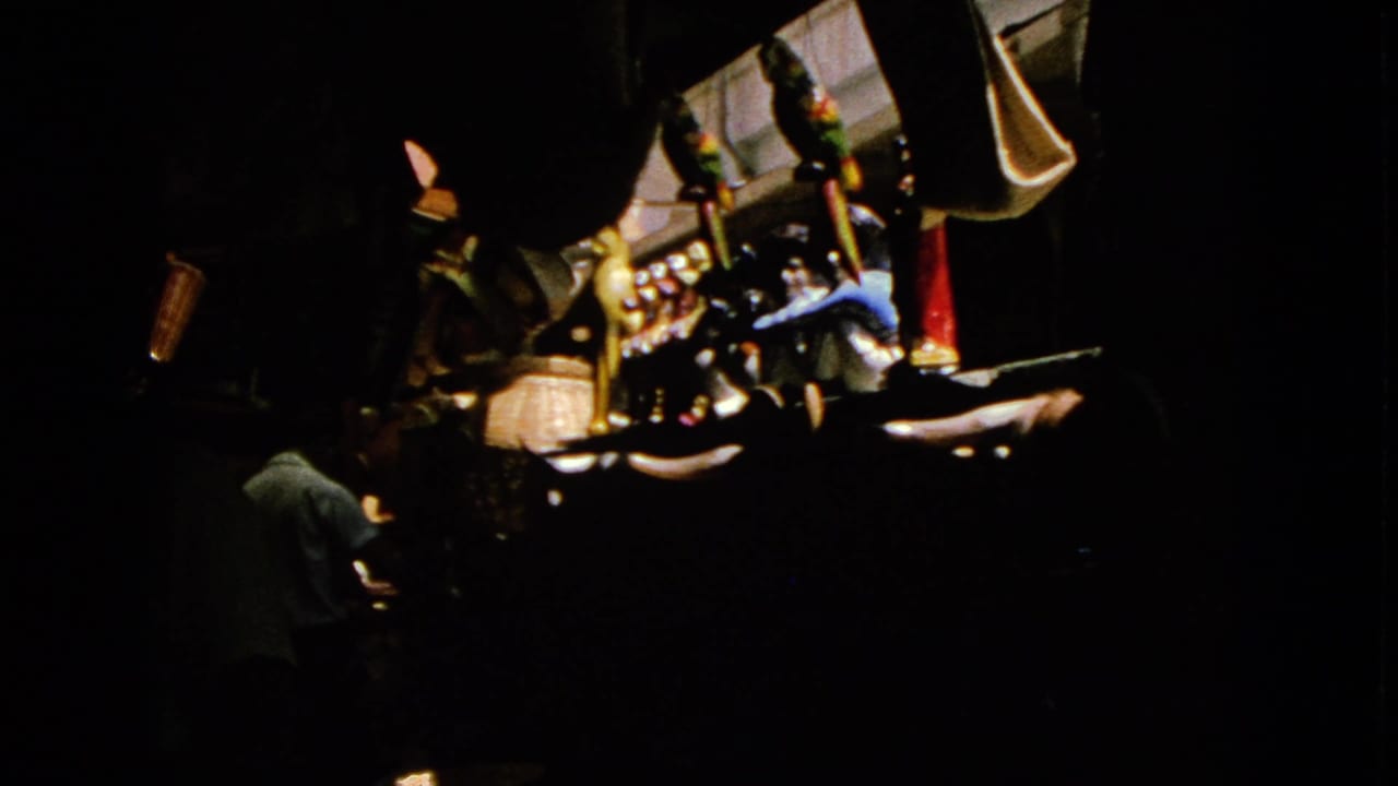 Dim interior with an adult near illuminated gaming machines and hanging fixtures.
