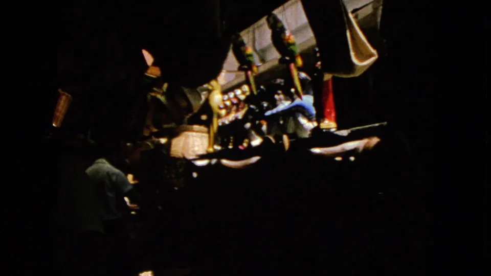 1963 8mm frame from Barrington metadata showing a dark gambling or amusement interior with an adult near glowing machine fronts.
