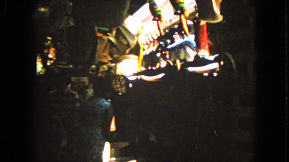 A dark 8mm Barrington interior frame shows glowing gaming equipment with adults partly obscured by shadow and handheld blur.