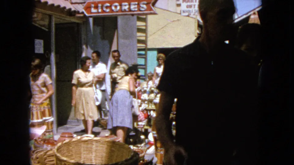 1963 Barrington street-shopping scene with people standing beside outdoor baskets, goods, and visible shop signage.