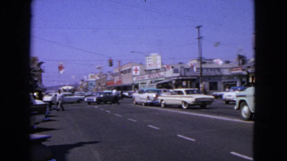 Barrington, Illinois street scene from 1963 with classic cars, storefronts, overhead signals, utility lines, and a visible Red Cross sign.