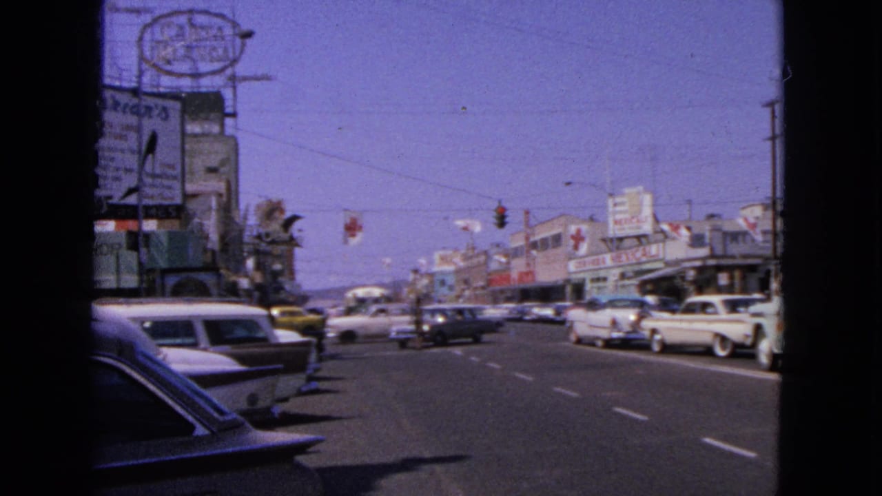 Barrington street scene in 1963 with roadside signage, classic automobiles, traffic signals, and a busy retail block.