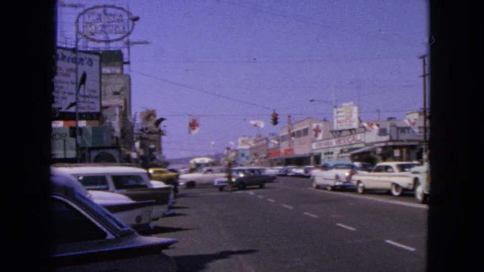 Barrington street scene in 1963 with roadside signage, classic automobiles, traffic signals, and a busy retail block.