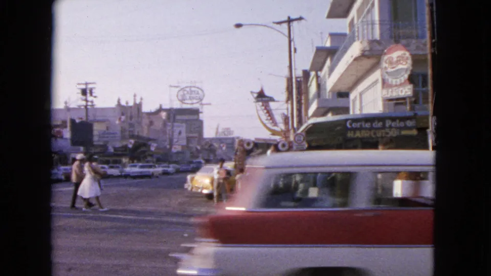 1963 Barrington, Illinois street view with pedestrians crossing, classic cars, storefront signs, and mid-century commercial buildings.
