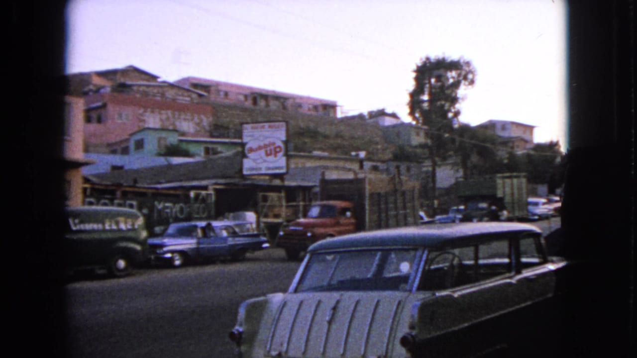 Street with parked classic cars, hillside buildings, and a Bubble Up sign in the background.