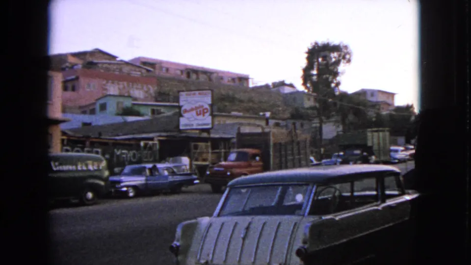 1963 Barrington, Illinois street view with parked early-1960s cars, storefront shade, hillside buildings, and a Bubble Up sign.