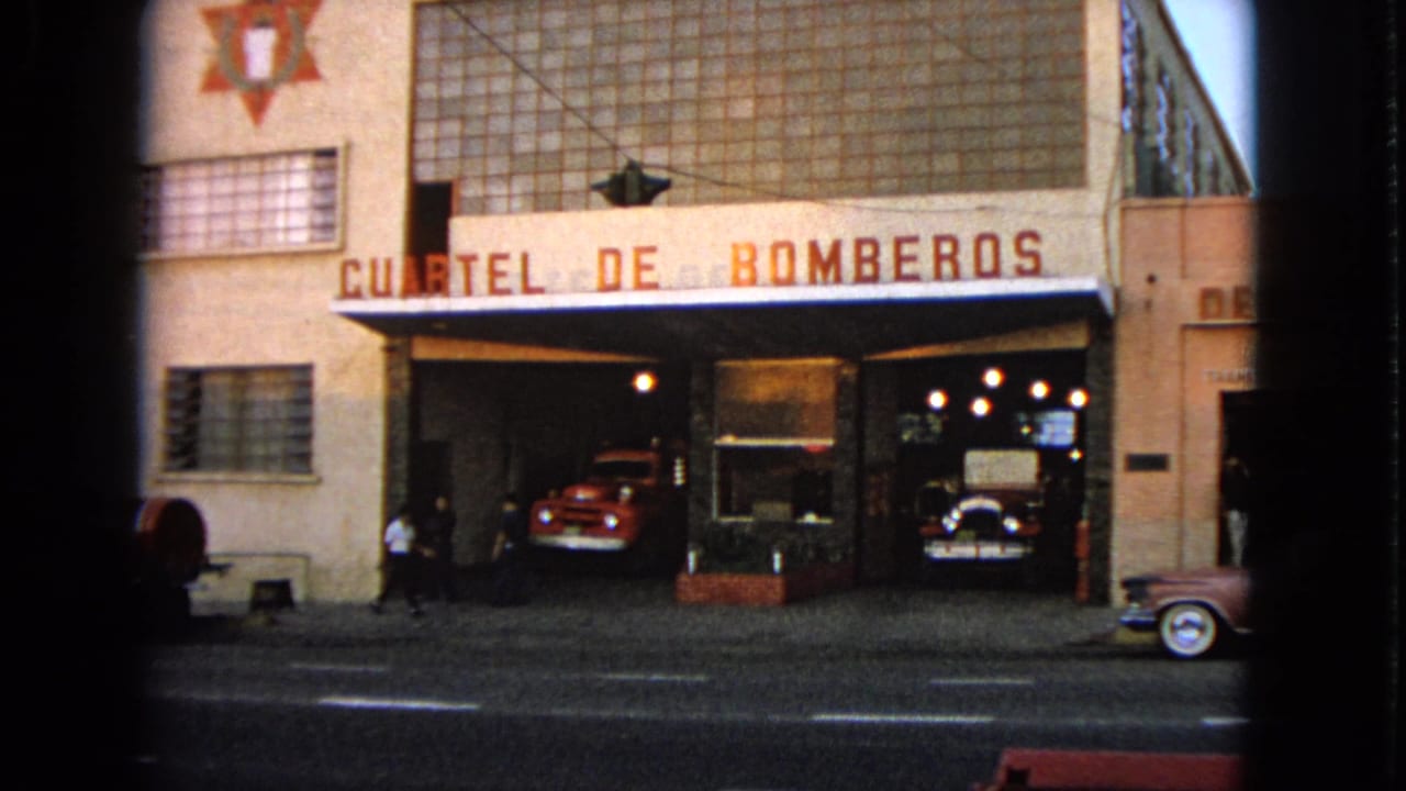 Fire station exterior with Cuartel de Bomberos sign and red fire trucks inside the bays.