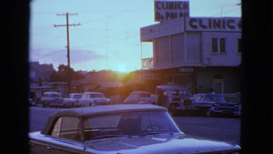 1963 Barrington, Illinois closer parking-lot view with a convertible roof, parked cars, clinic signage, and sunset glare.