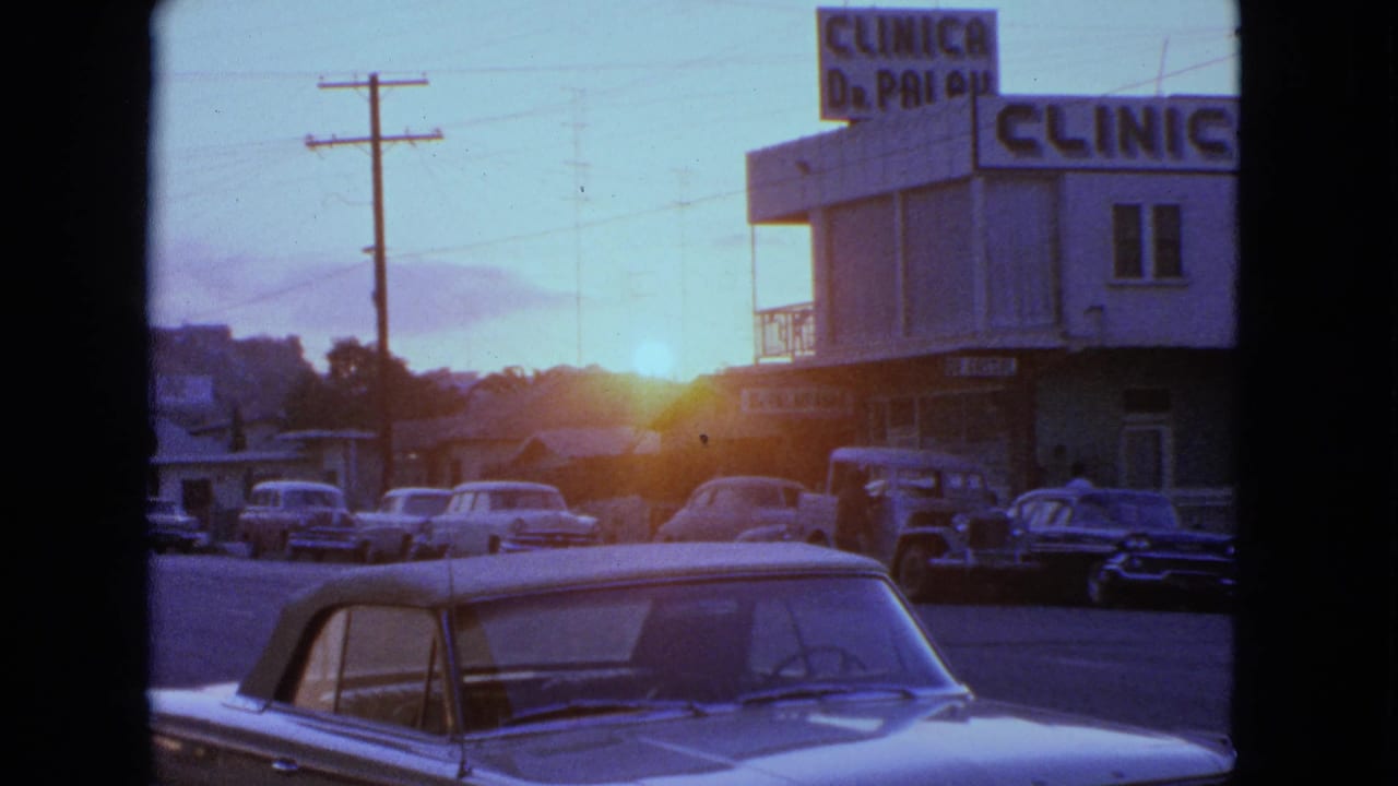 Sunset street with parked cars, utility poles, and a clinic building sign.