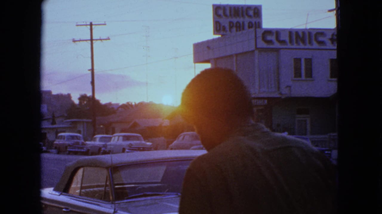Man in silhouette passes in front of a sunset street and clinic sign.
