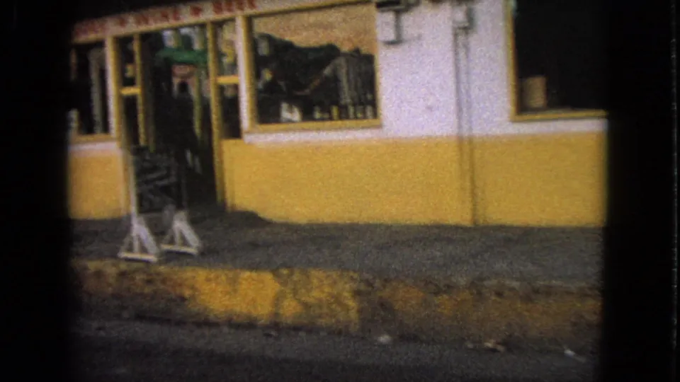 Barrington storefront detail from 1963 showing a yellow-and-white facade, recessed entrance, window display, sidewalk, and curb.