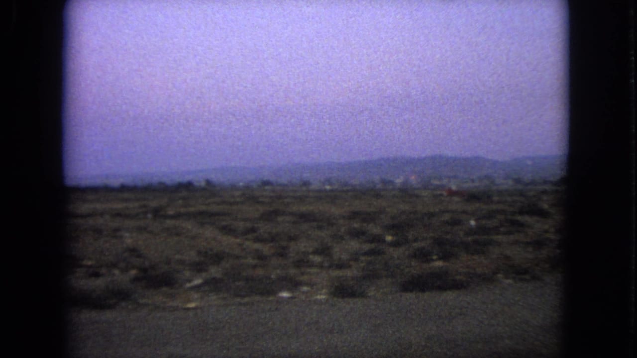 1963 Barrington, Illinois 8mm frame showing a blurred open roadside landscape under a hazy sky.