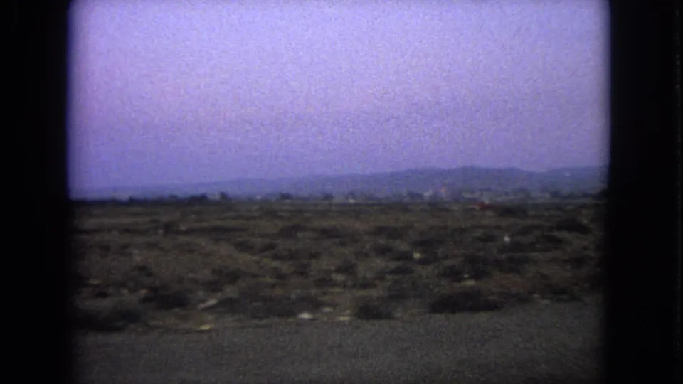 1963 Barrington, Illinois 8mm frame showing a blurred open roadside landscape under a hazy sky.