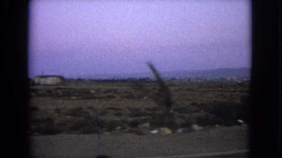 1963 Barrington, Illinois moving-car frame with scrubby roadside terrain and a dark foreground blur.