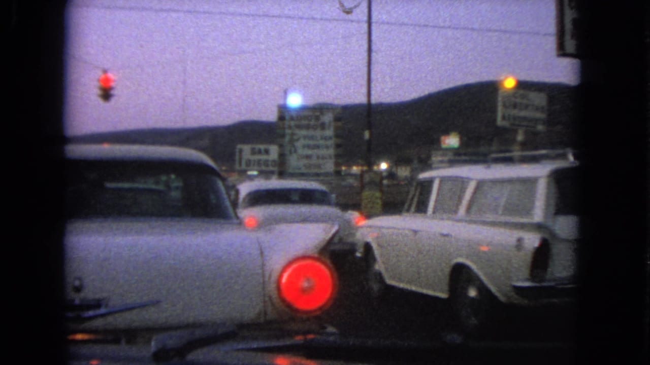 1963 Barrington, Illinois street view with classic cars stopped at a red light, including a white station wagon and business signs.