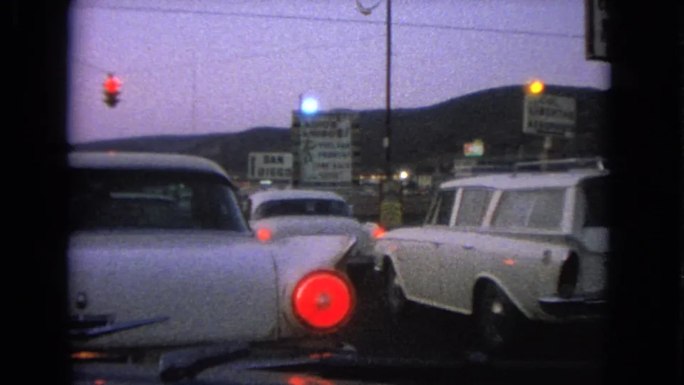 1963 Barrington, Illinois street view with classic cars stopped at a red light, including a white station wagon and business signs.