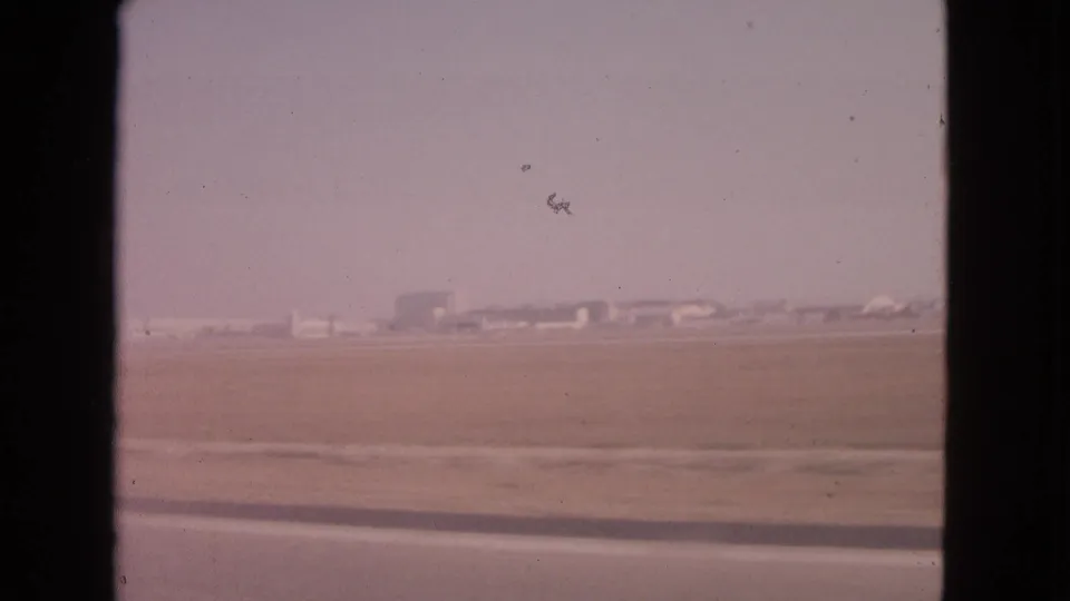 Barrington, Illinois home-movie frame from 1963 with a hazy open landscape and low horizon buildings seen from inside a moving car.