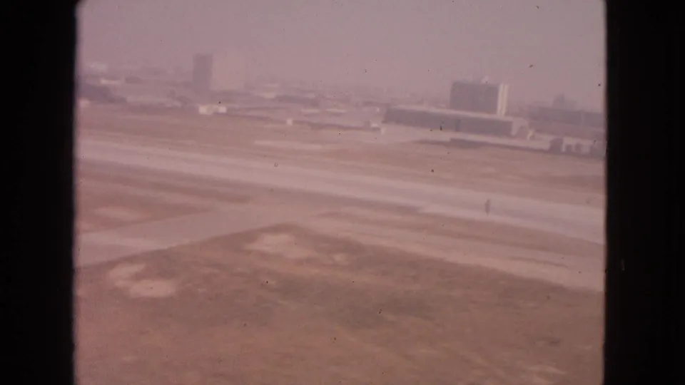 1963 Barrington, Illinois airport footage showing a runway, broad taxiway pavement, distant structures, and pink-shifted 8mm color.