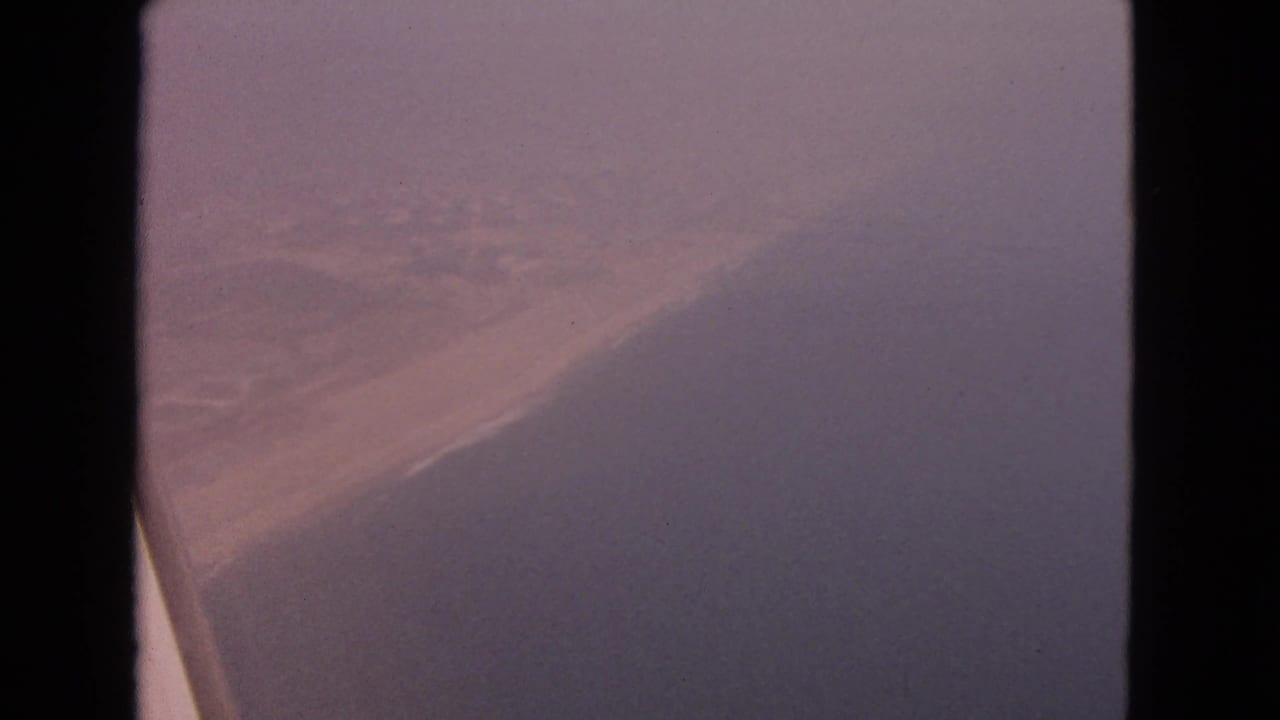 Hazy view from an aircraft window with a dark edge and soft purple-gray fog.