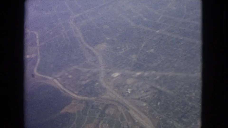 Likely Barrington-area aerial footage from 1963, with curving roads, wooded land, fields, and small structures visible through vintage film framing.