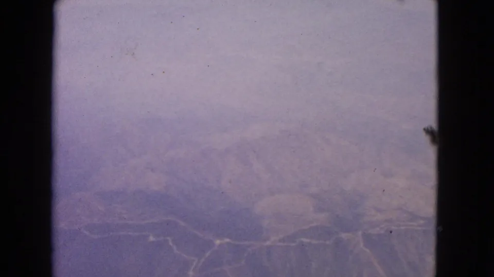 Hazy 1963 aerial home-movie frame likely near Barrington, Illinois, with faint landforms, roads, possible water, and strong exposure wash.