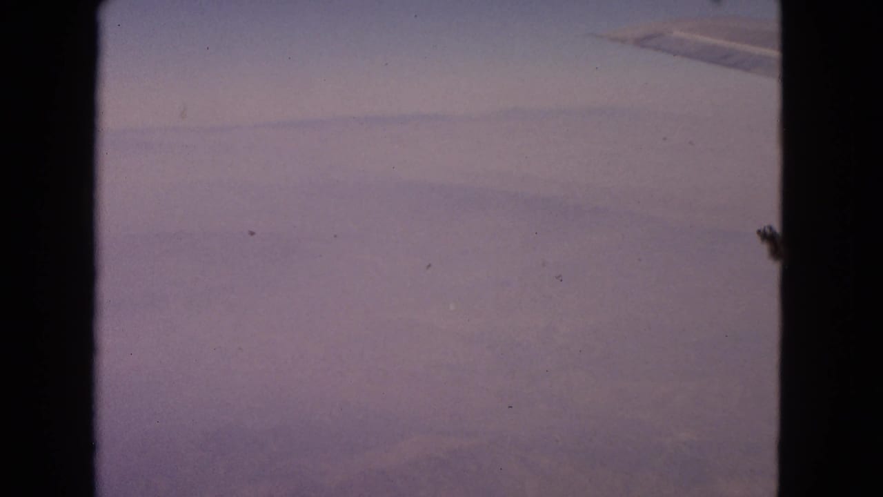 Cloudy aerial view with airplane wing tip near the upper right.