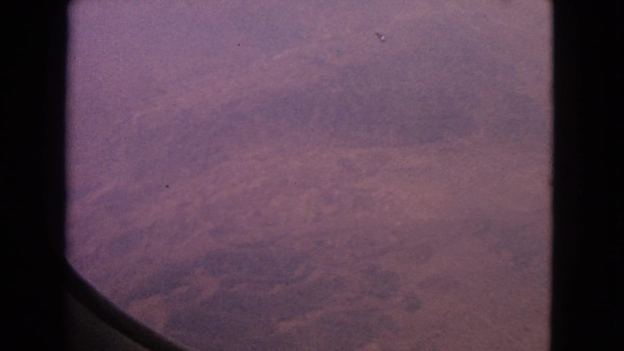1963 8mm airplane-window view with dark frame edges and reddish terrain below, associated with Barrington, Illinois metadata.