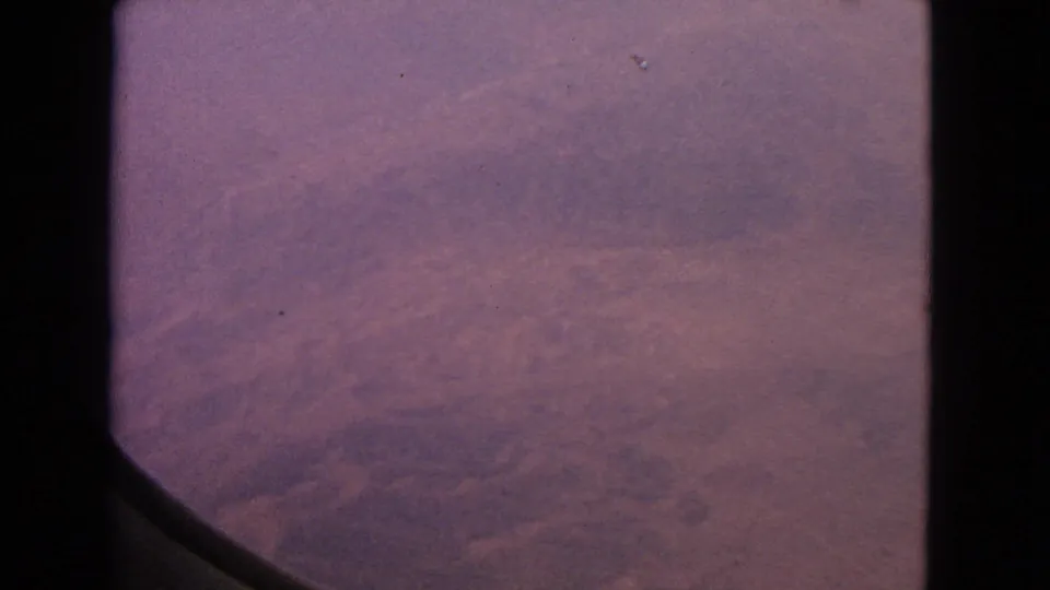 1963 8mm airplane-window view with dark frame edges and reddish terrain below, associated with Barrington, Illinois metadata.