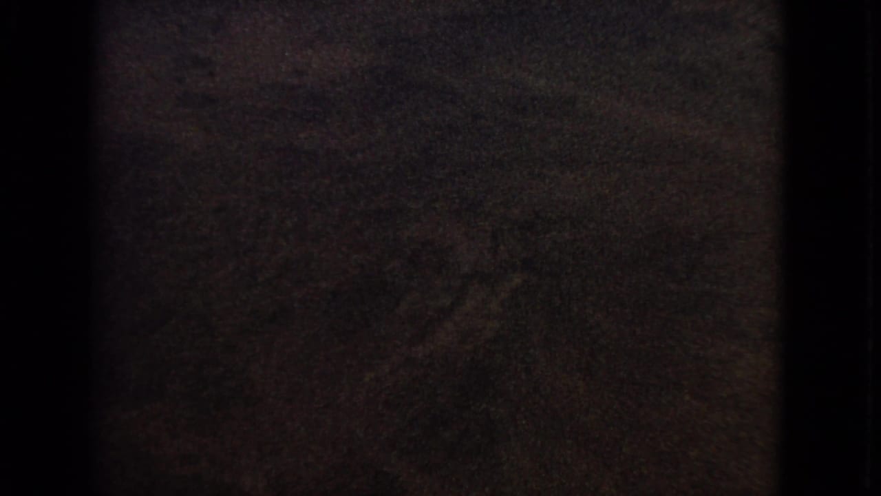 A darkened 1963 8mm airplane-window view with little visible detail as the exposure falls toward twilight.