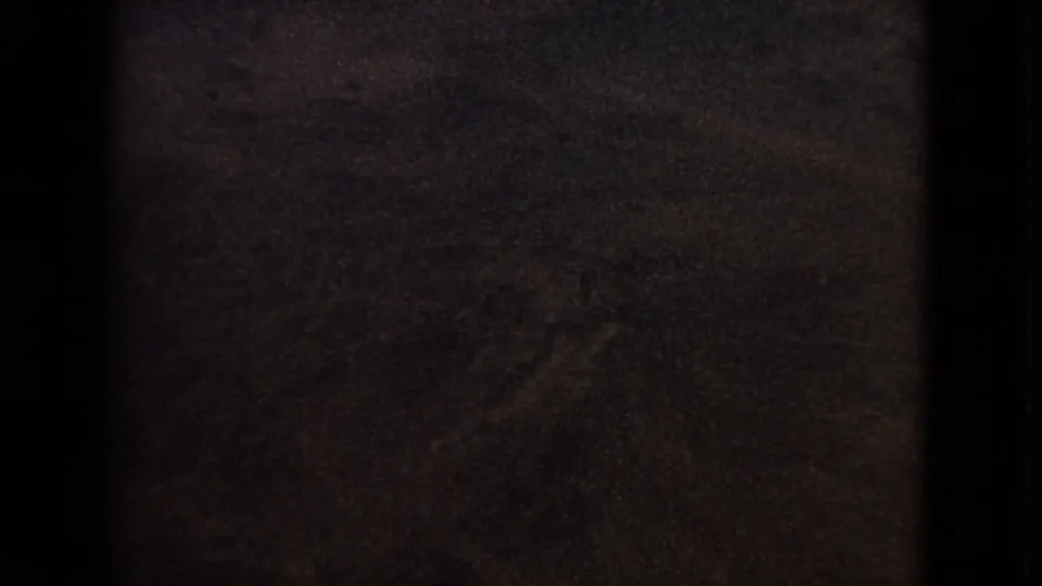 A darkened 1963 8mm airplane-window view with little visible detail as the exposure falls toward twilight.