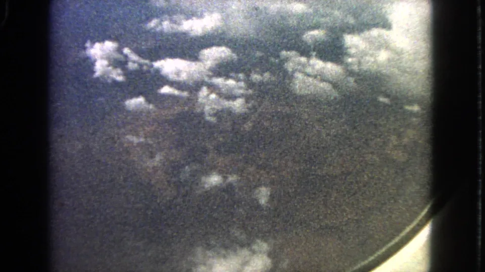 1963 home-movie aerial view through an airplane window, with clouds over a hazy landscape near Barrington, Illinois.