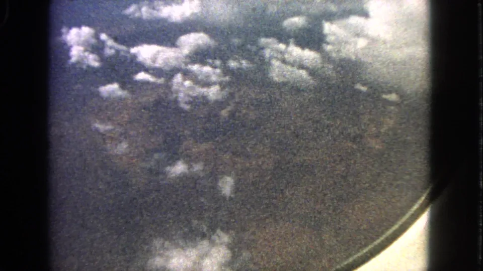 Grainy 1963 8mm aerial view of clouds and land from a passenger airplane window near Barrington, Illinois.