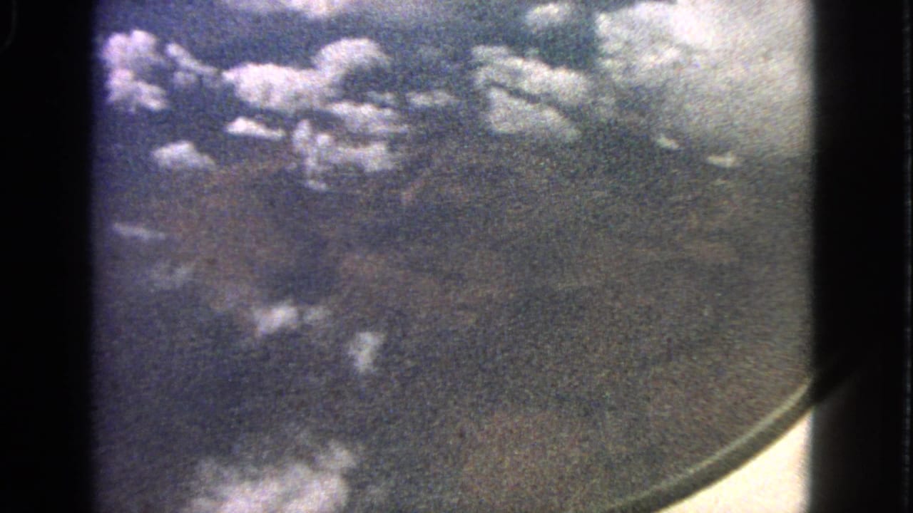 Cloudy aerial view with the aircraft window edge curving along the right side.